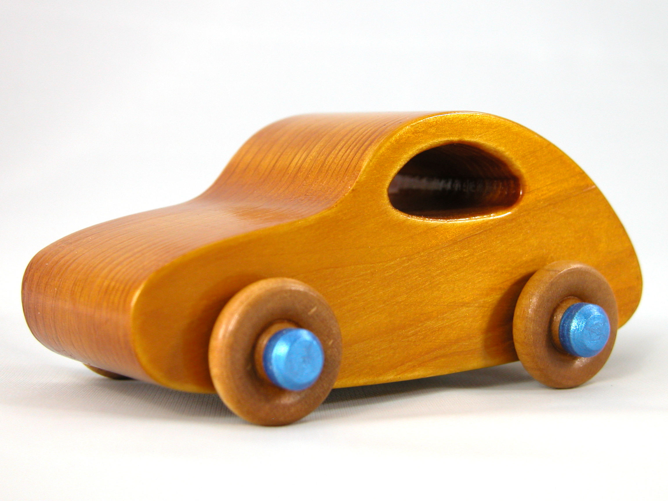 Handmade wooden toy car with an amber shellac finish and metallic sapphire blue trim, modeled after the classic 1957 Bug.