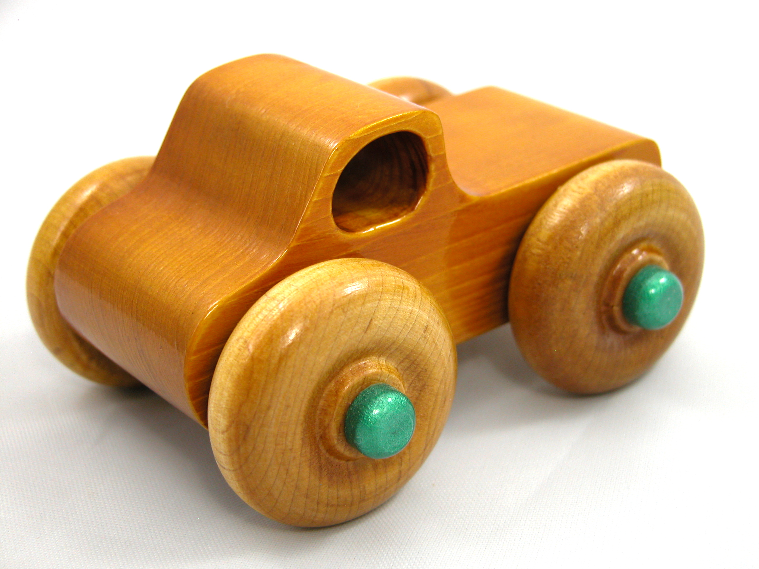 Handmade wooden toy monster truck, crafted in a toymaker's shop with traditional woodworking tools. Finished in amber shellac and metallic emerald green acrylic paint, this sturdy and durable toy is perfect for kids of all ages.