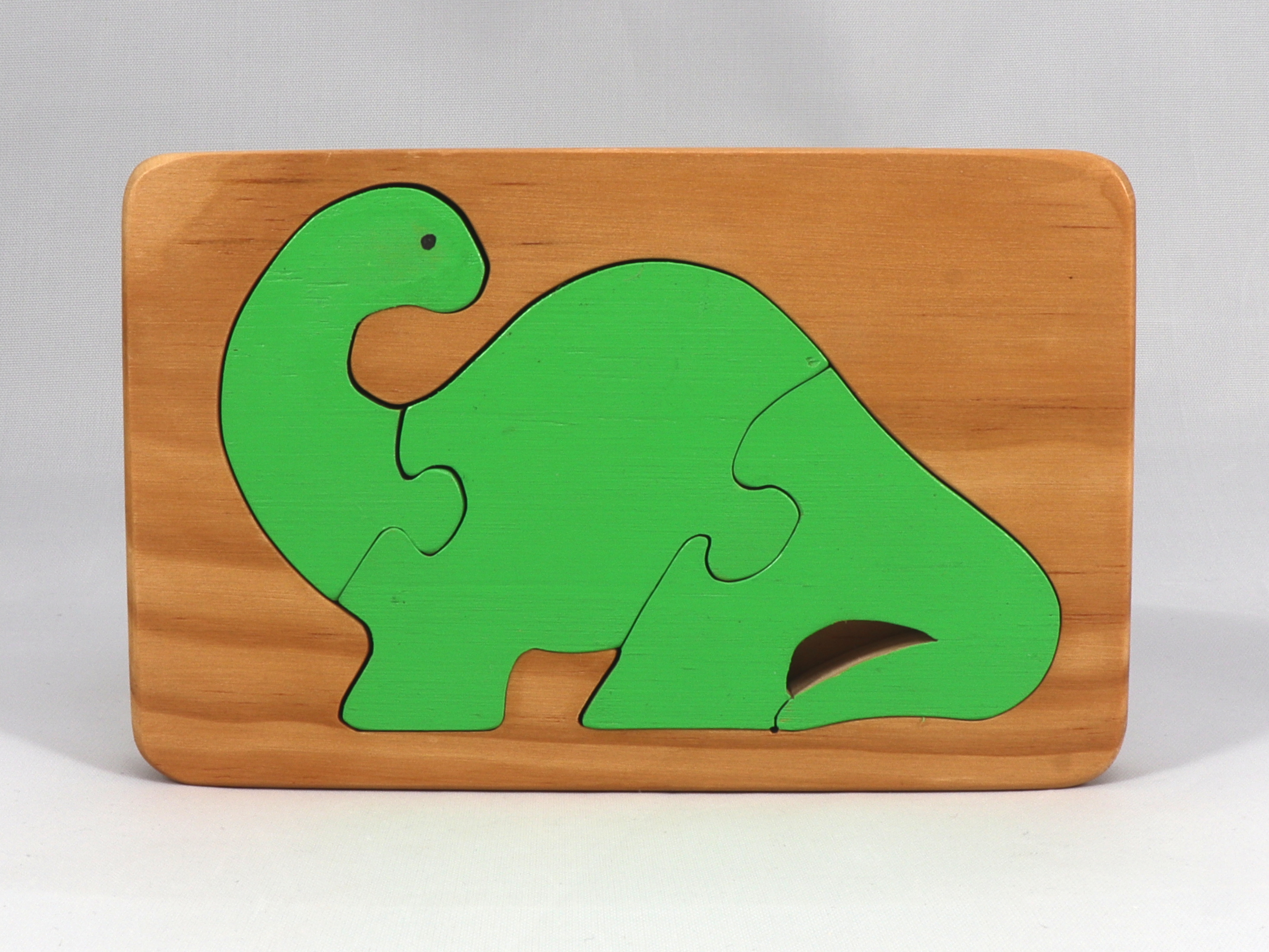 Handmade three-piece wooden dinosaur tray puzzle finished with amber shellac and green acrylic paint.