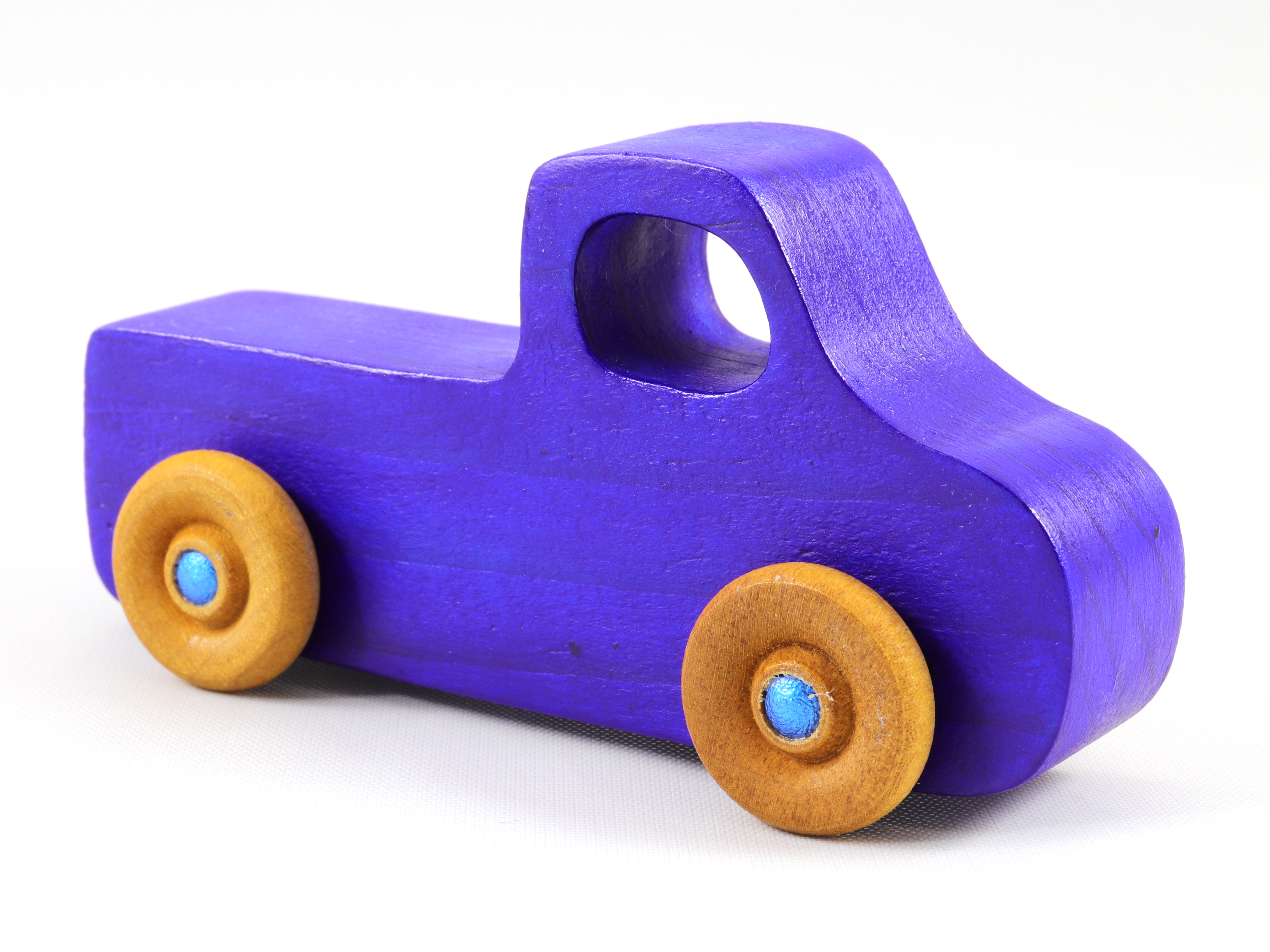 A handmade wooden toy pickup truck painted with bright blue and metallic sapphire blue paint. The wheels are finished with non-marring amber shellac. This toy is part of my Play Pal Collection.
